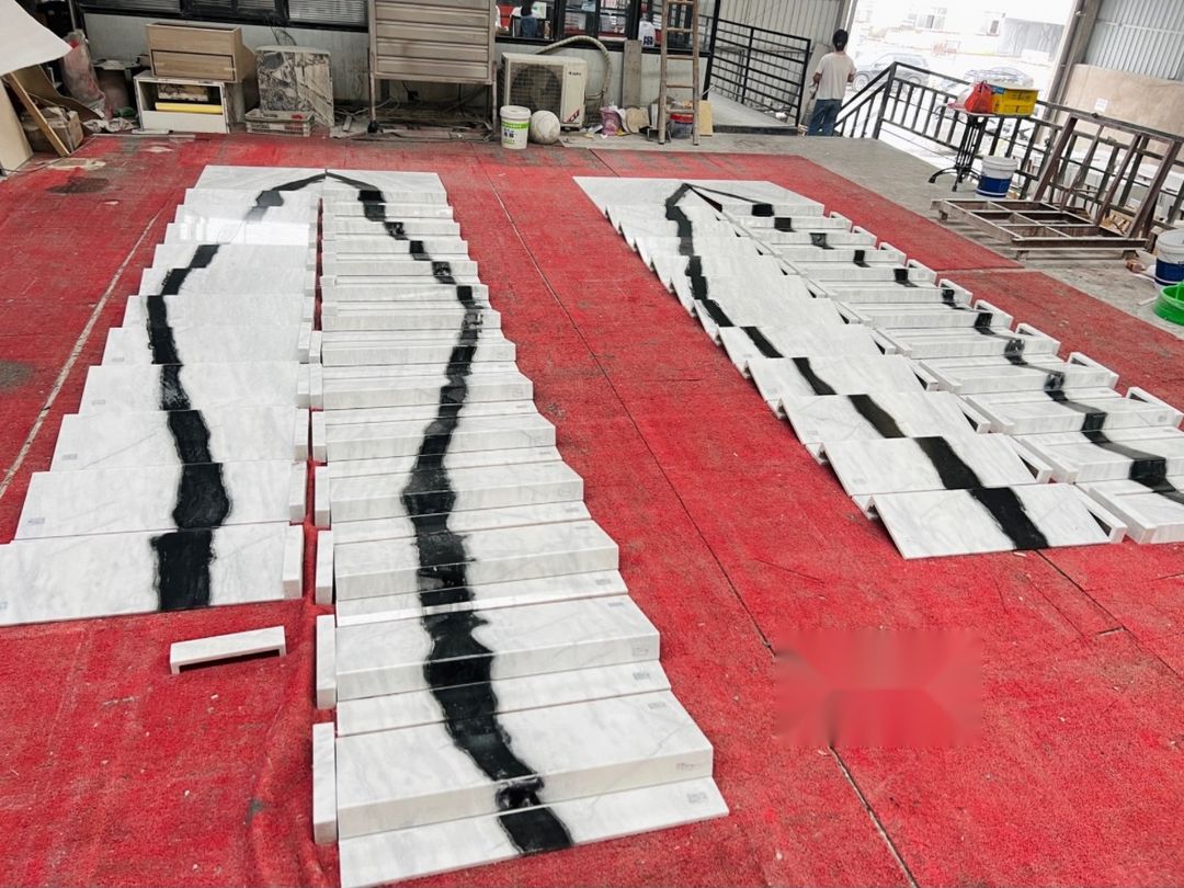 Panda White marble stair treads and companion pieces grouped on a workshop floor