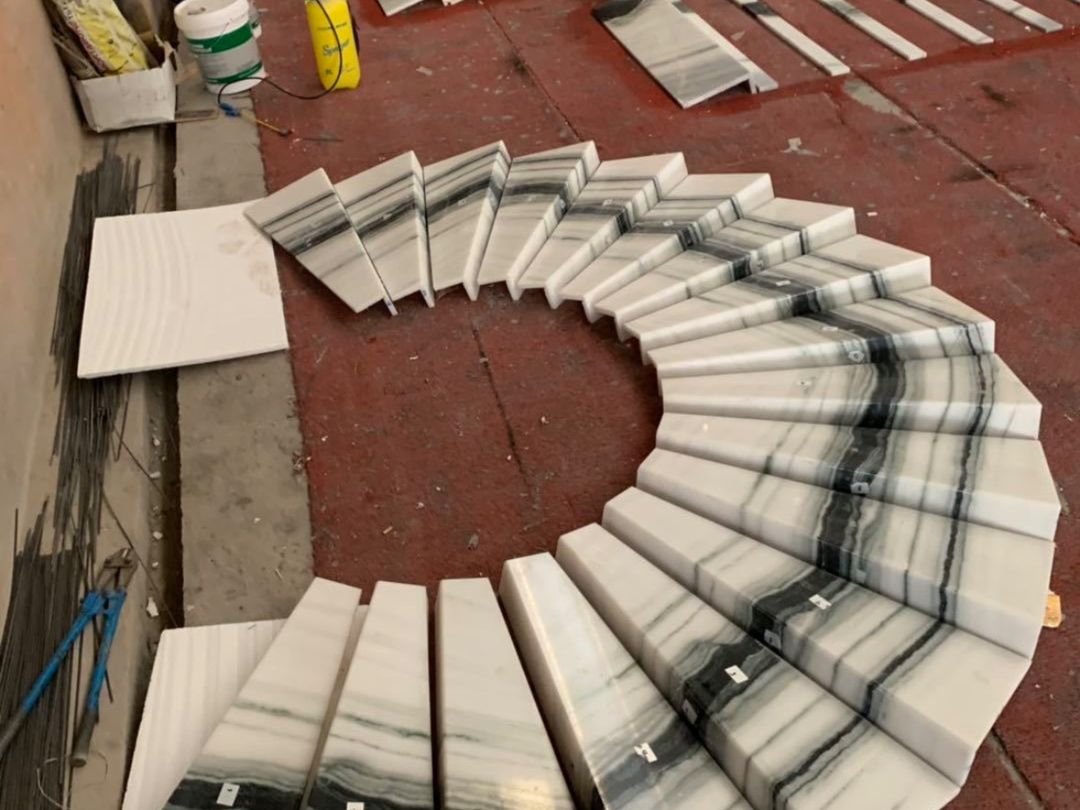 Worker inspecting Panda White marble staircase pieces during factory dry assembly