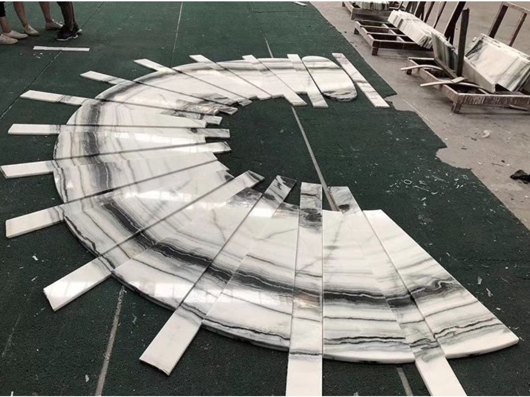 Fan-shaped Panda White marble winder treads arranged for a curved staircase dry fit